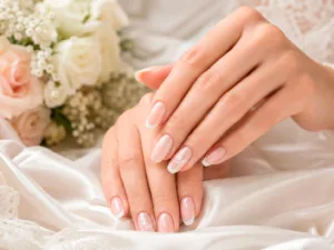 Uñas para boda con french blanco, base nude y detalles delicados sobre fondo floral.